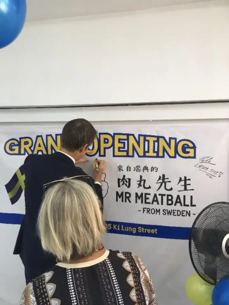 Ryggtavla på en manlig person som skriver på en väggaffisch med åskådare i förgrunden.