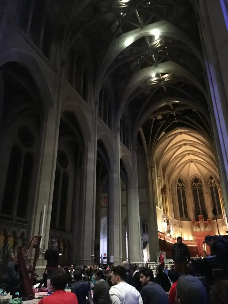Inifrån en katedral, Grace Cathedral. Högt i tak och mörkt belyst, människor i nederkanten på bilden som besöker.