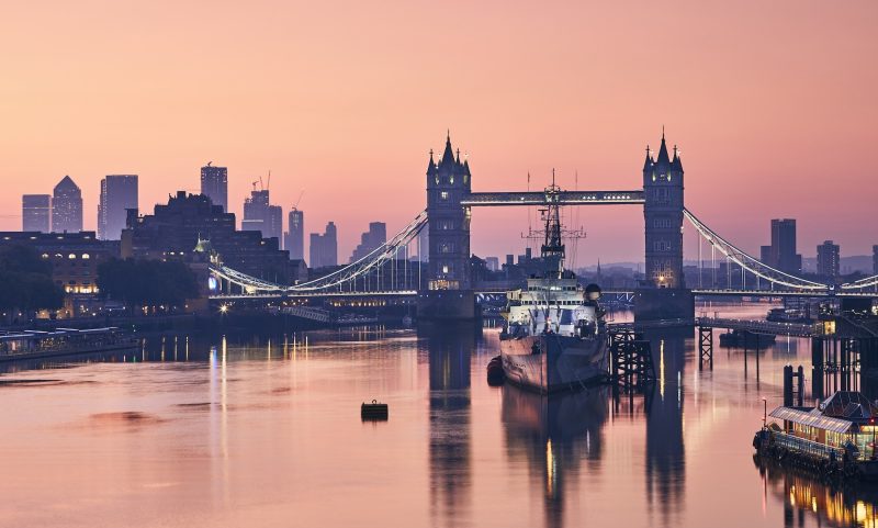 Skyline över london och Tower Bridge. En bro i bakgrunden av vatten på kvällen.