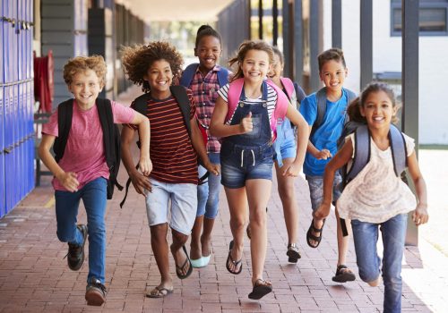 En grupp skolbarn springer på en skolgård dagtid.
